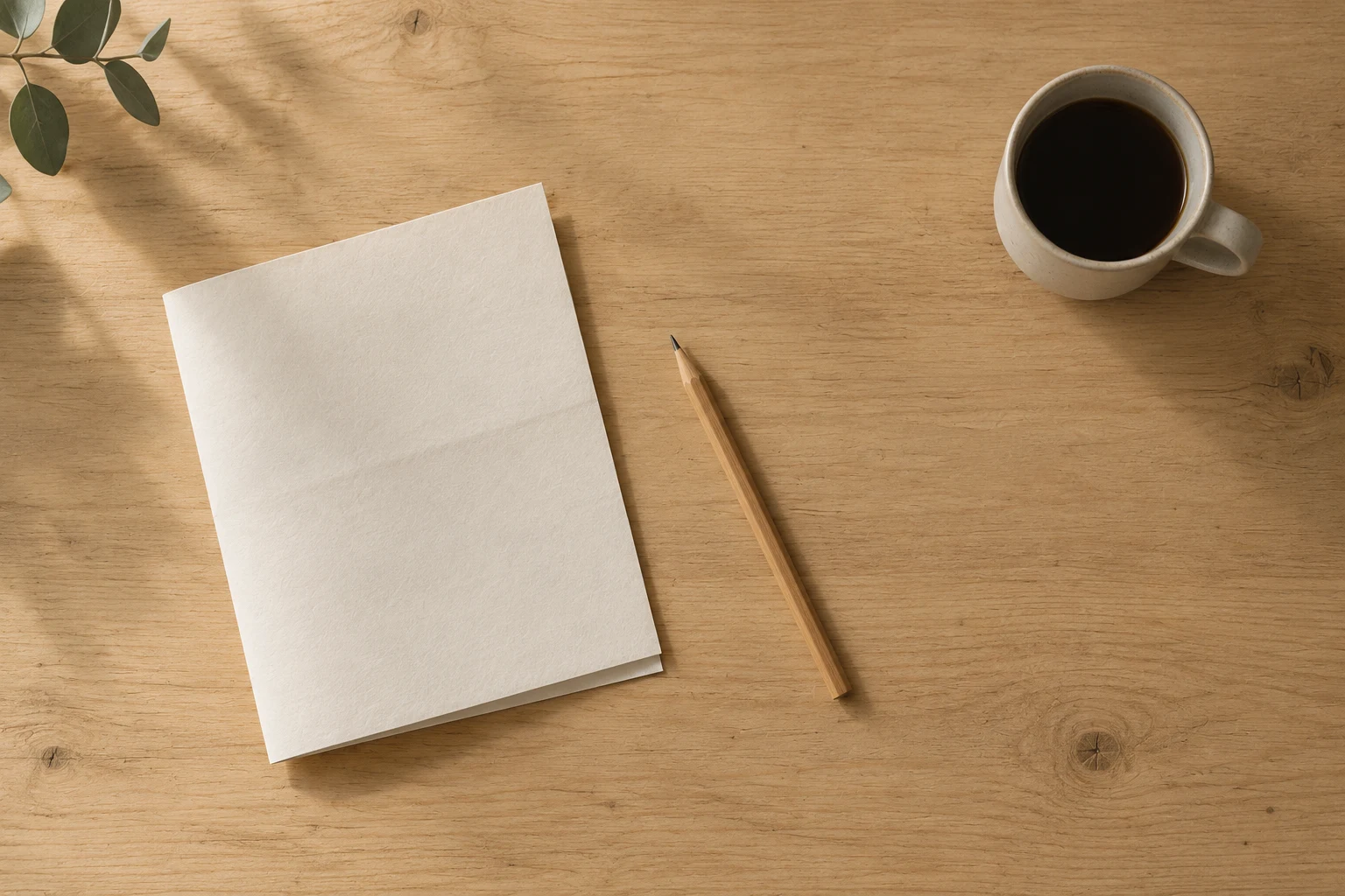 Schreibtisch von oben mit gefaltetem Papier, Bleistift und einer Tasse Kaffee